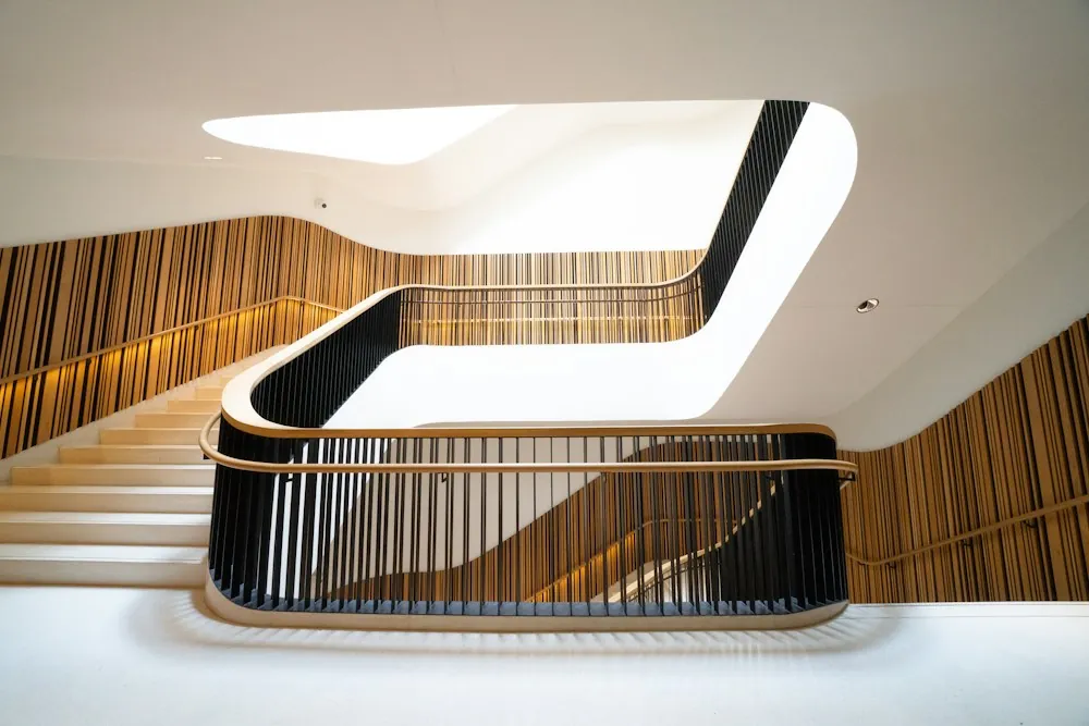 Curved staircase with warm wooden panelling and a handrail inside a modern building