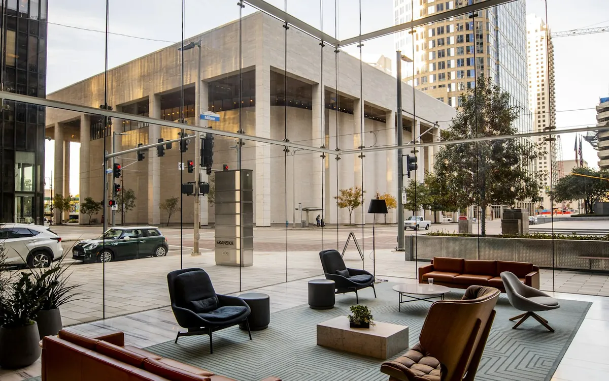 Tall glass-walled lobby with lounge seating and a city view