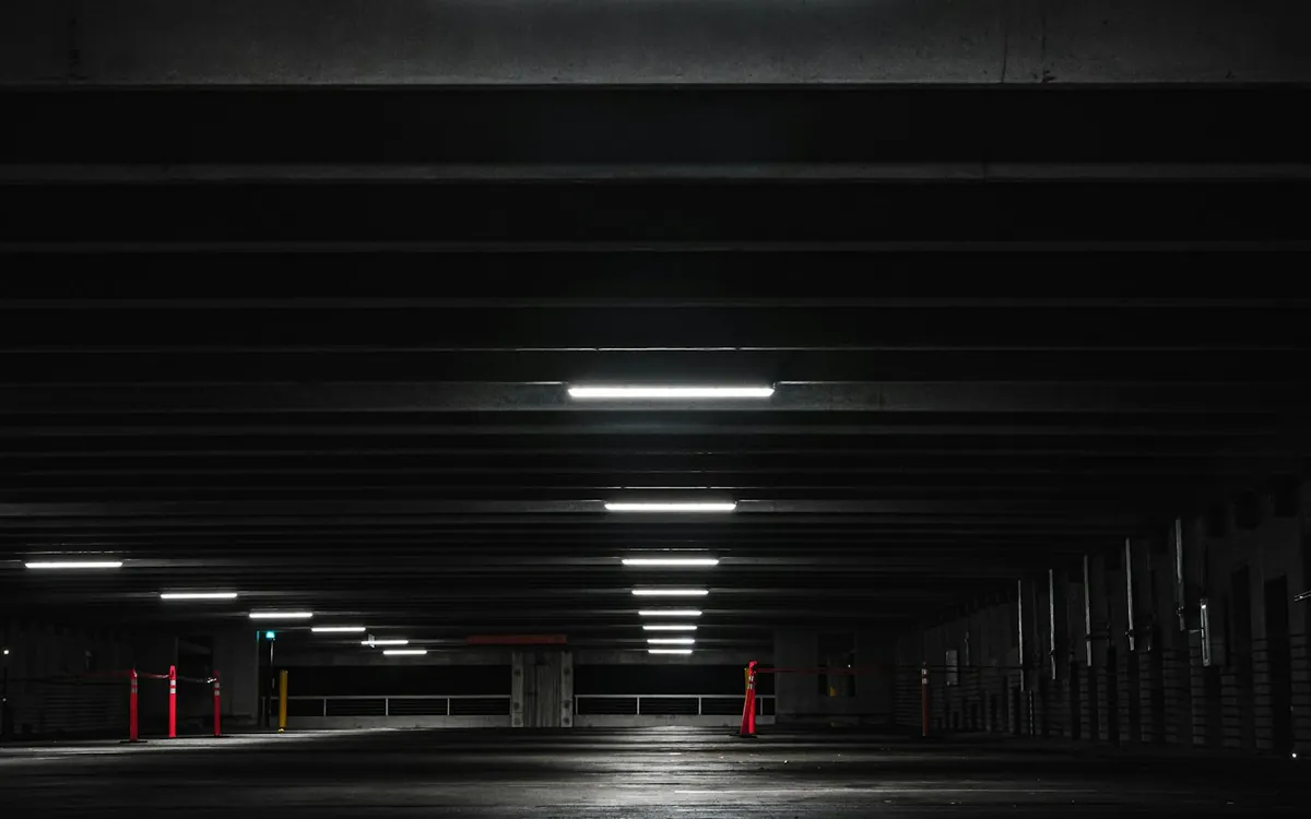 Dark empty parking level with a row of ceiling lights