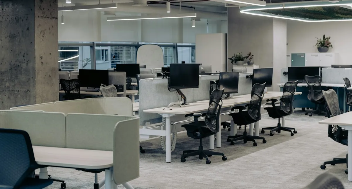 Open-plan office with white desks, ergonomic chairs and large windows