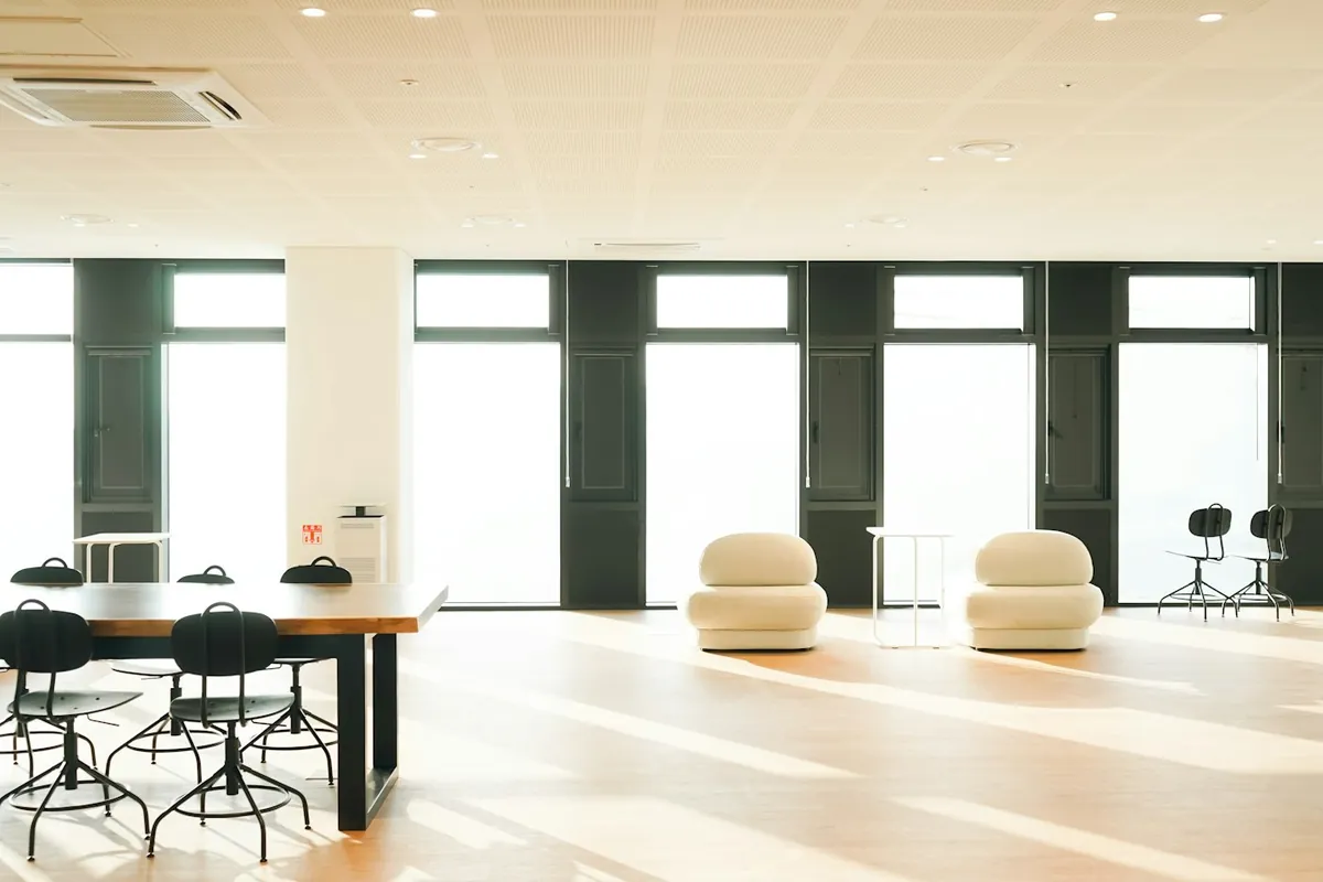 Bright airy room with tall windows, white chairs and a long table