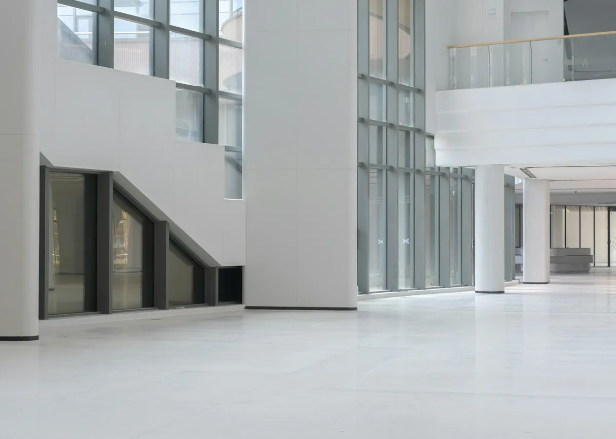 Large bright atrium with white columns, glass walls and a polished floor