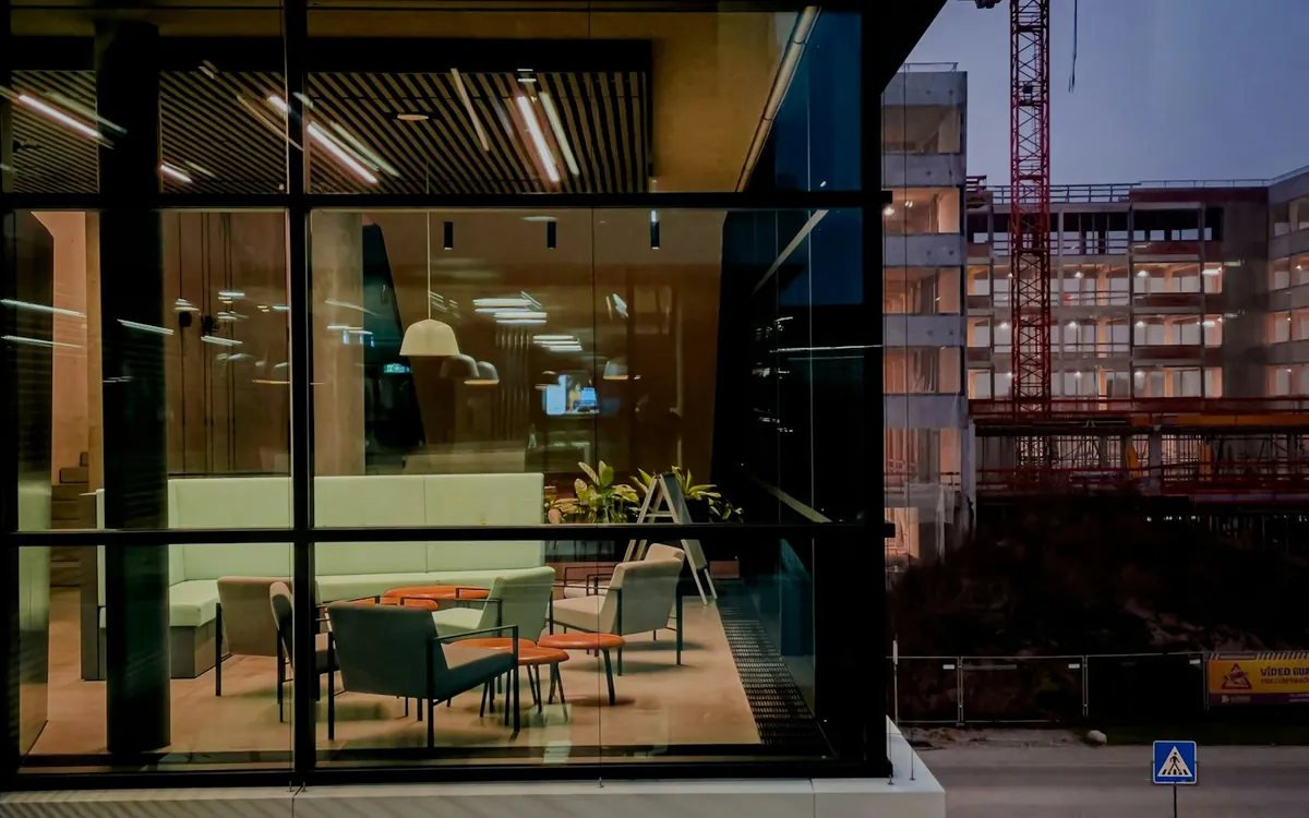 Glass-walled lounge lit at dusk next to a building site