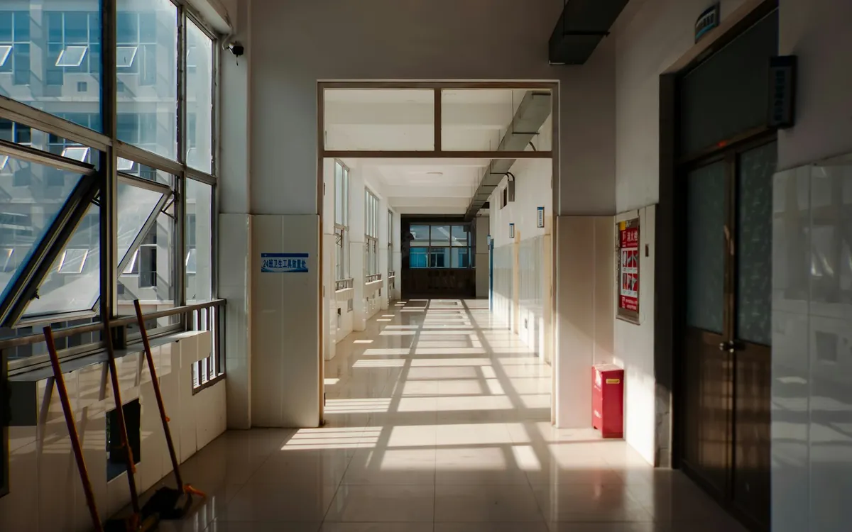 Sunlit hallway with large windows and a dark doorway
