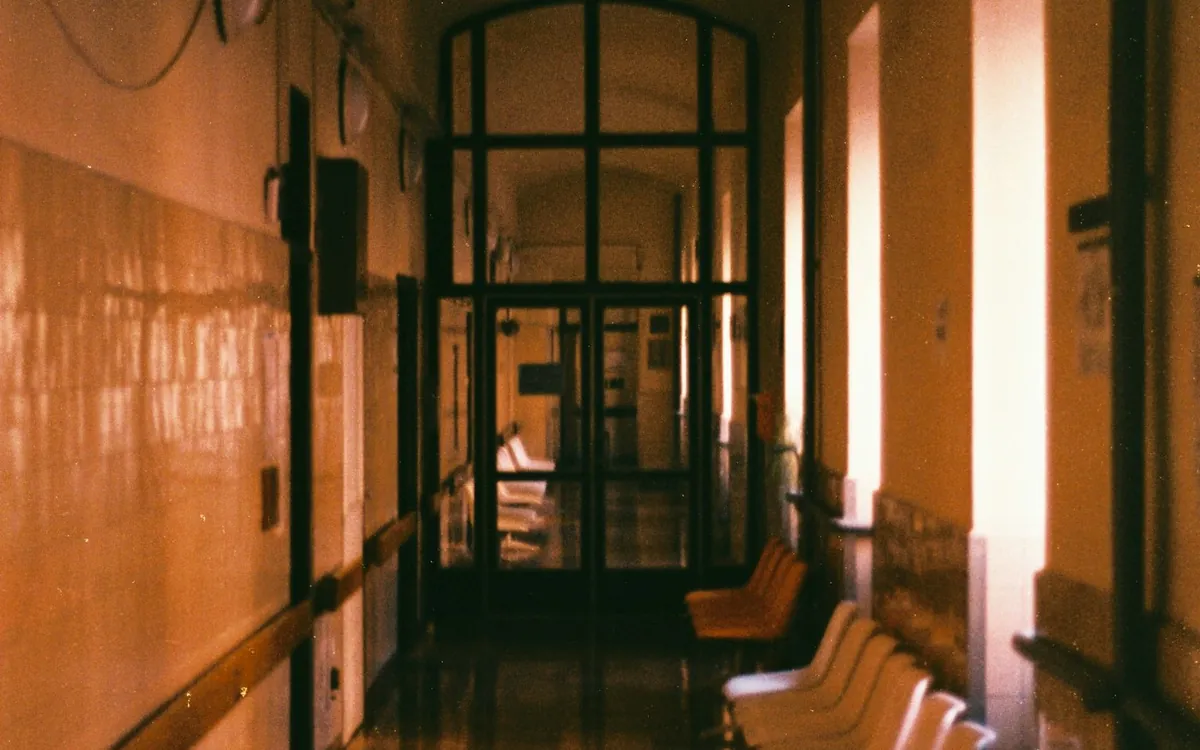 Warm-lit old corridor with tall windows and wooden seating