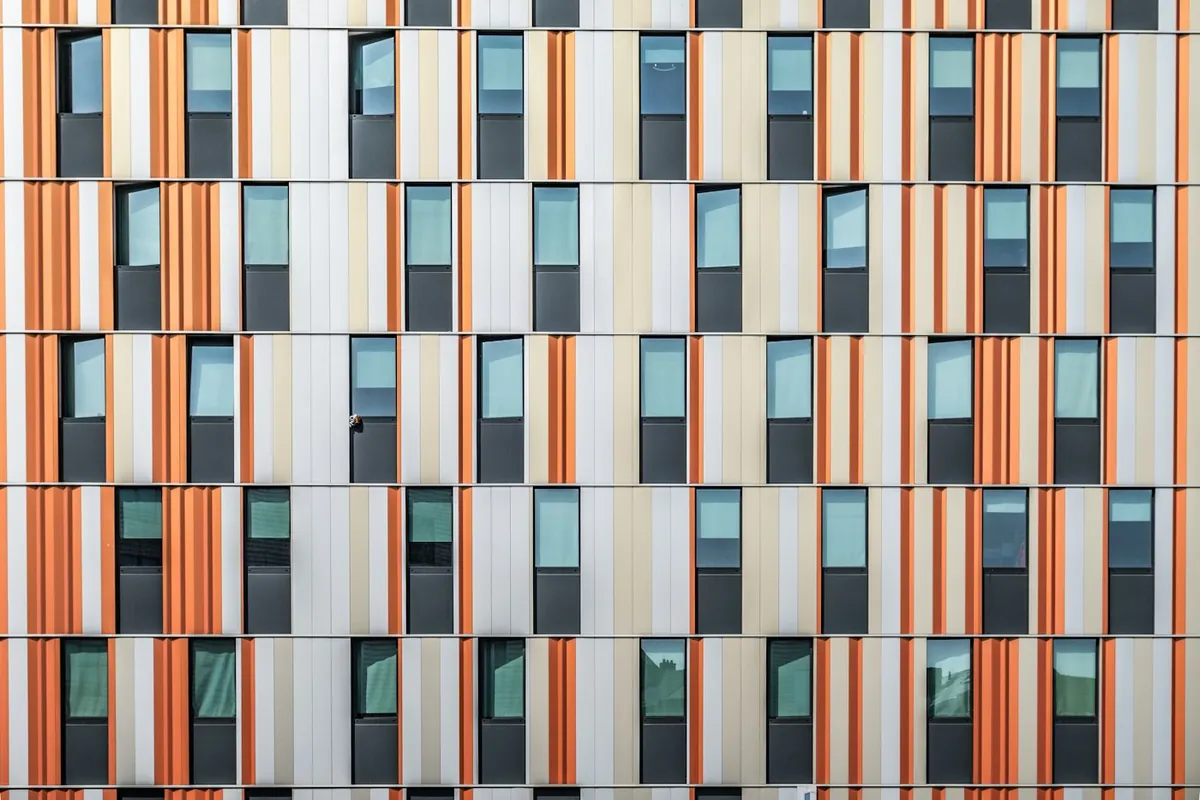 Building facade with orange and white vertical panels and small windows