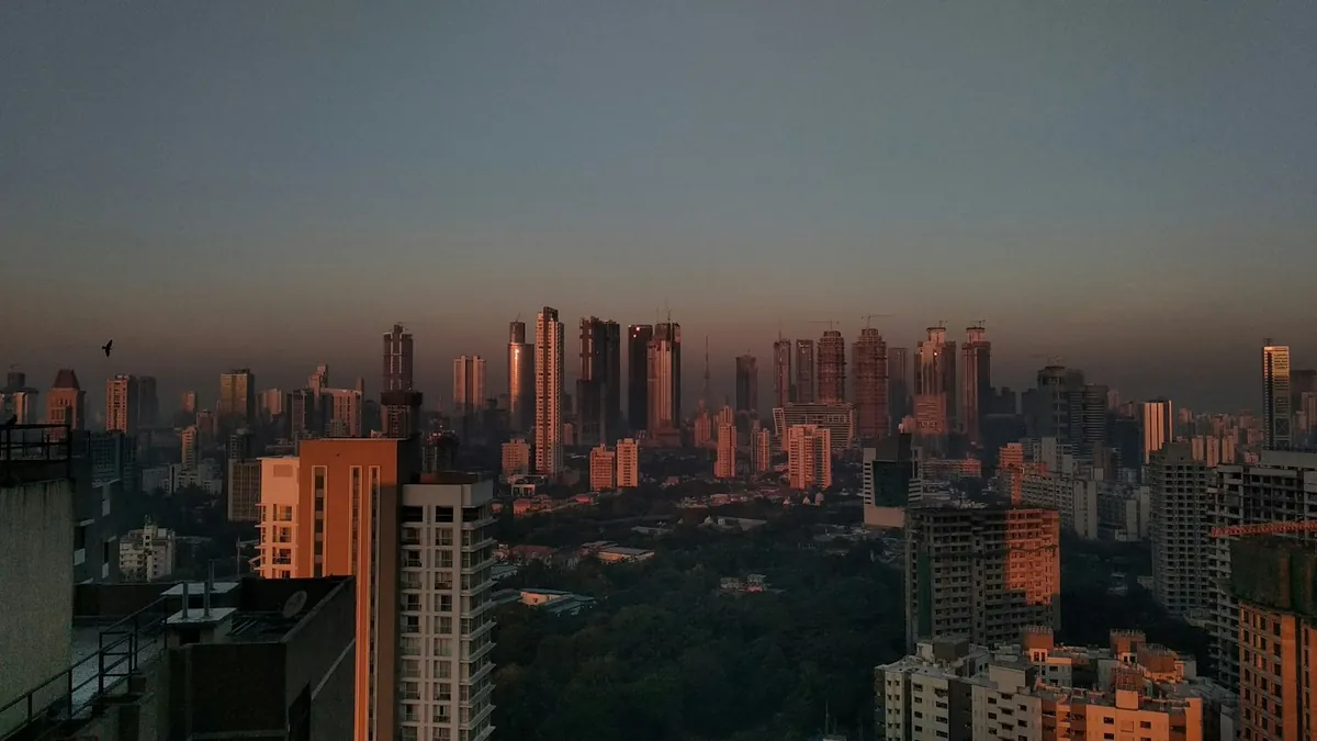 Skyline of tall towers glowing at sunset over a hazy city
