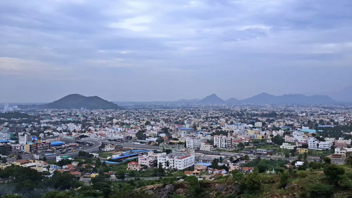 Wide view of a Bangalore-style city with low hills in the distance under clouds