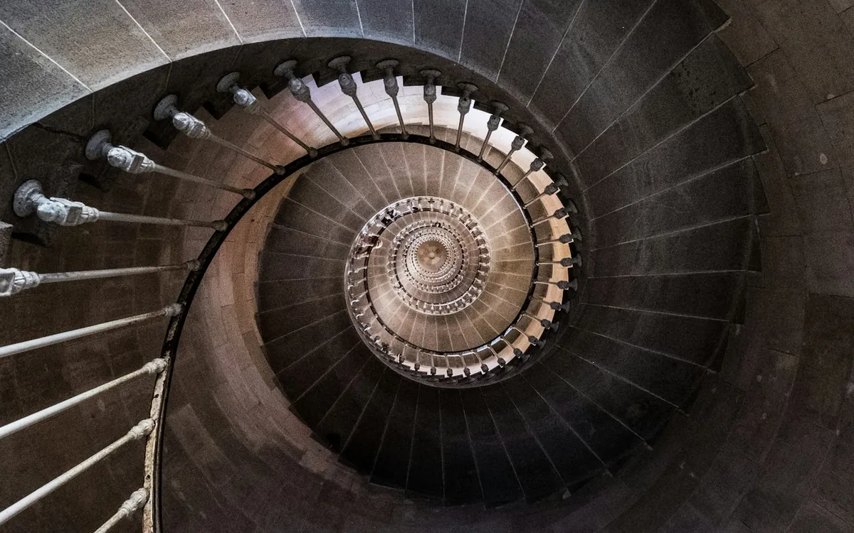 Looking down a dark spiral staircase with a circular pattern
