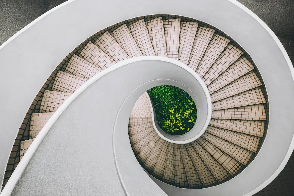 White spiral staircase seen from above with a garden at its centre