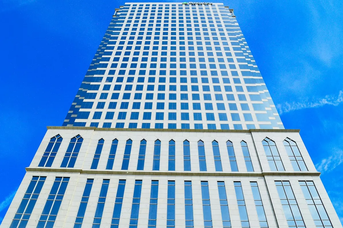 White and blue high-rise tower seen from below with a deep blue sky