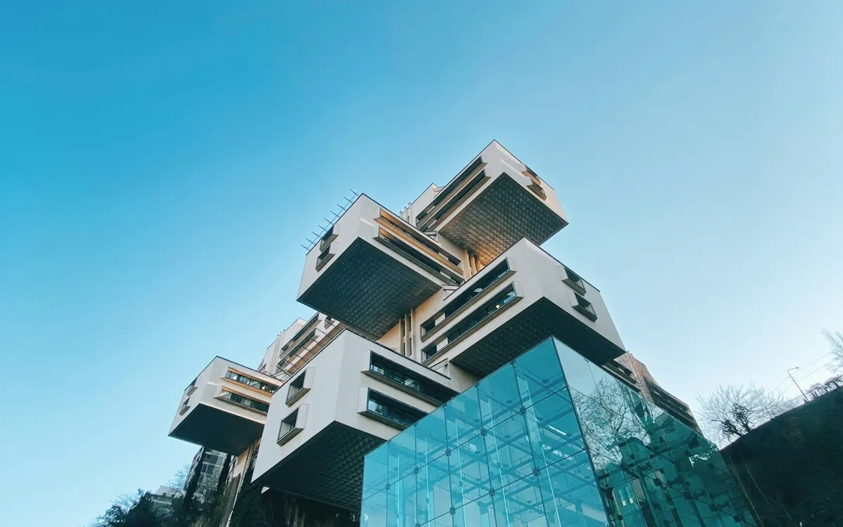 Angular glass building with stacked steel boxes on a hillside