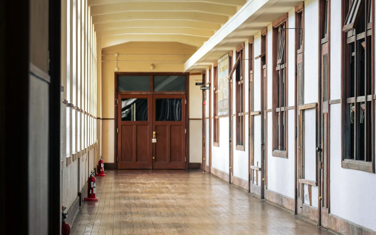 Long hallway with a wooden floor and tall windows on one side