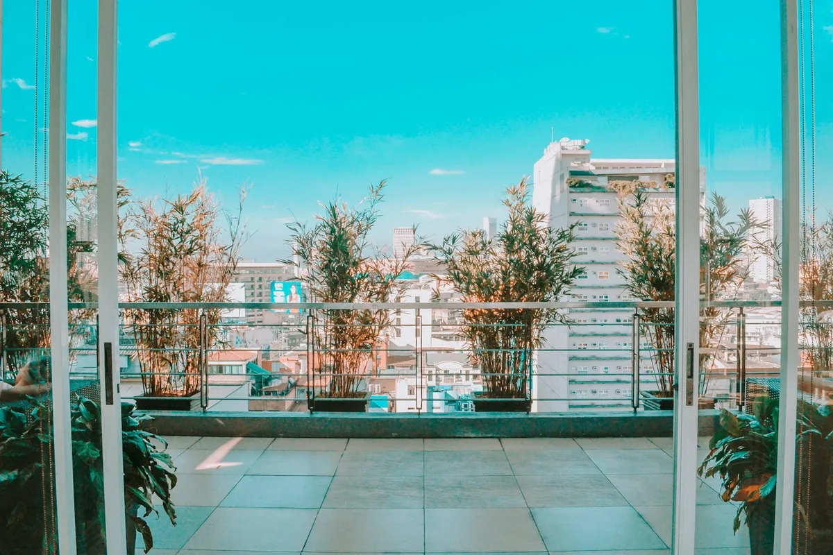 Glass-walled terrace with potted bamboo plants and city buildings beyond