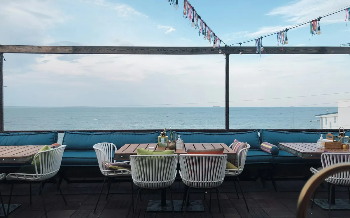 Sea-view terrace restaurant with white chairs and bunting under a bright sky