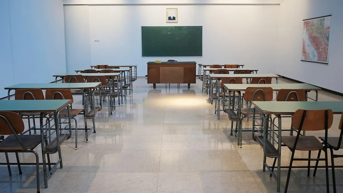 Bright empty classroom with rows of desks and a green chalkboard