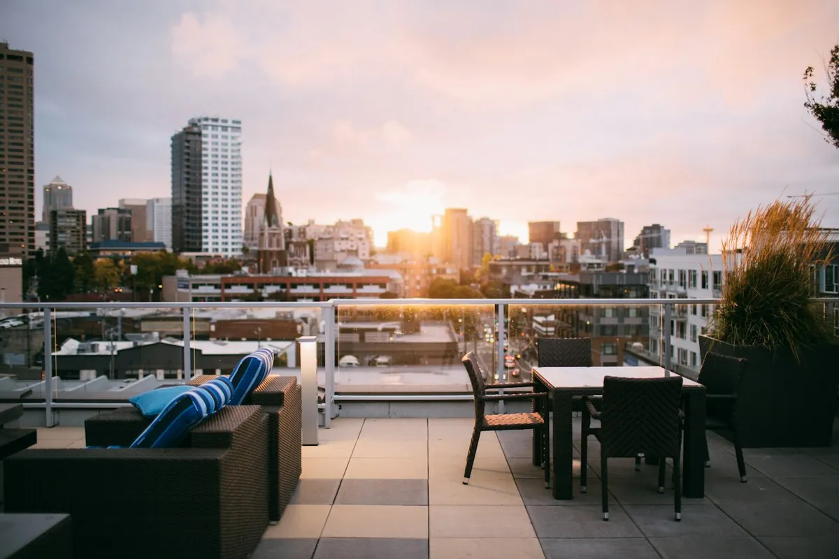City terrace at sunset with lounge seating, a dining table and glass railing
