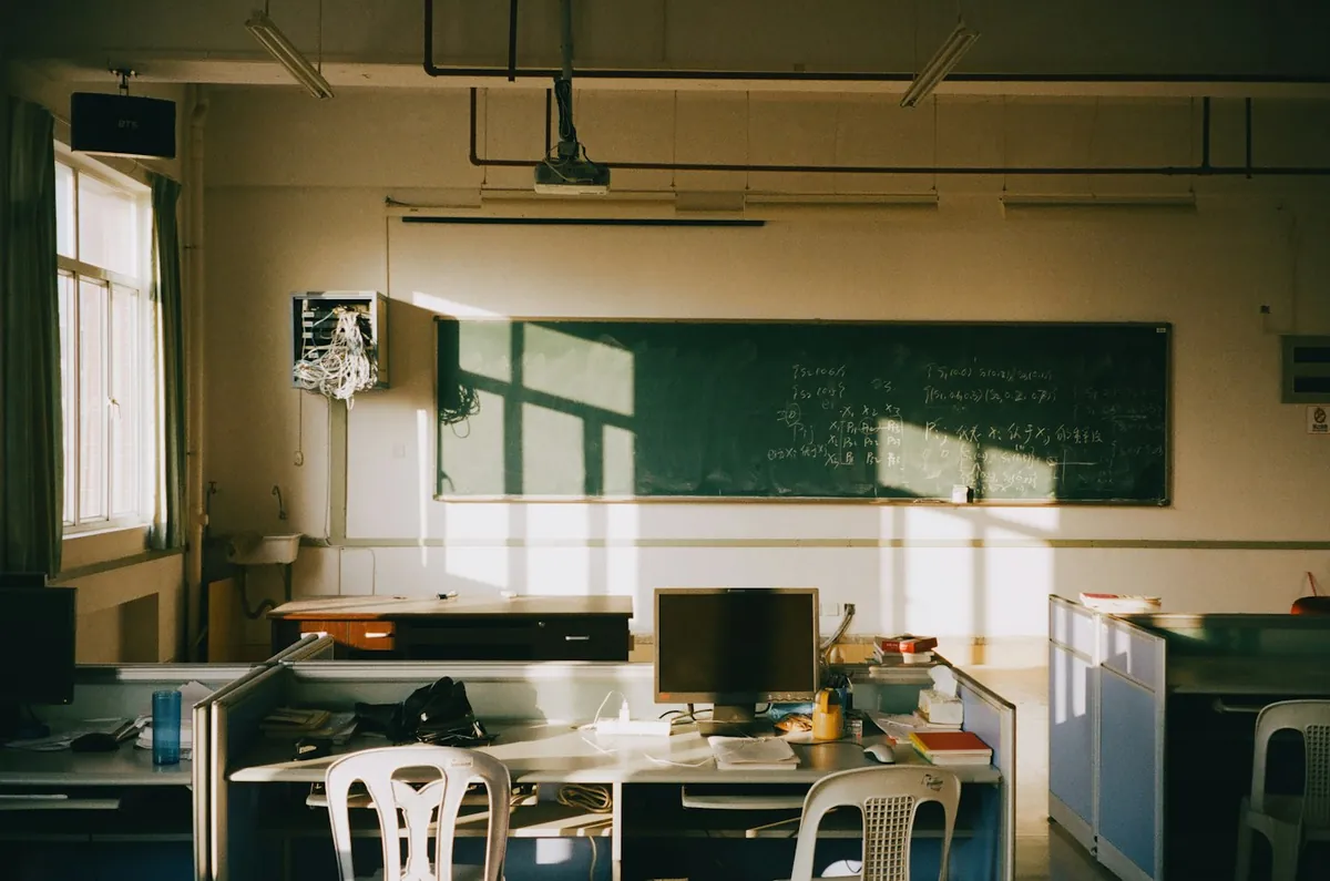 Sunlit classroom with a green board and wooden desks