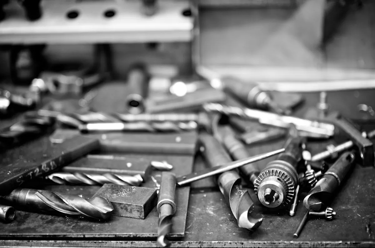 Drill bits and metal tools on a workshop table in black and white