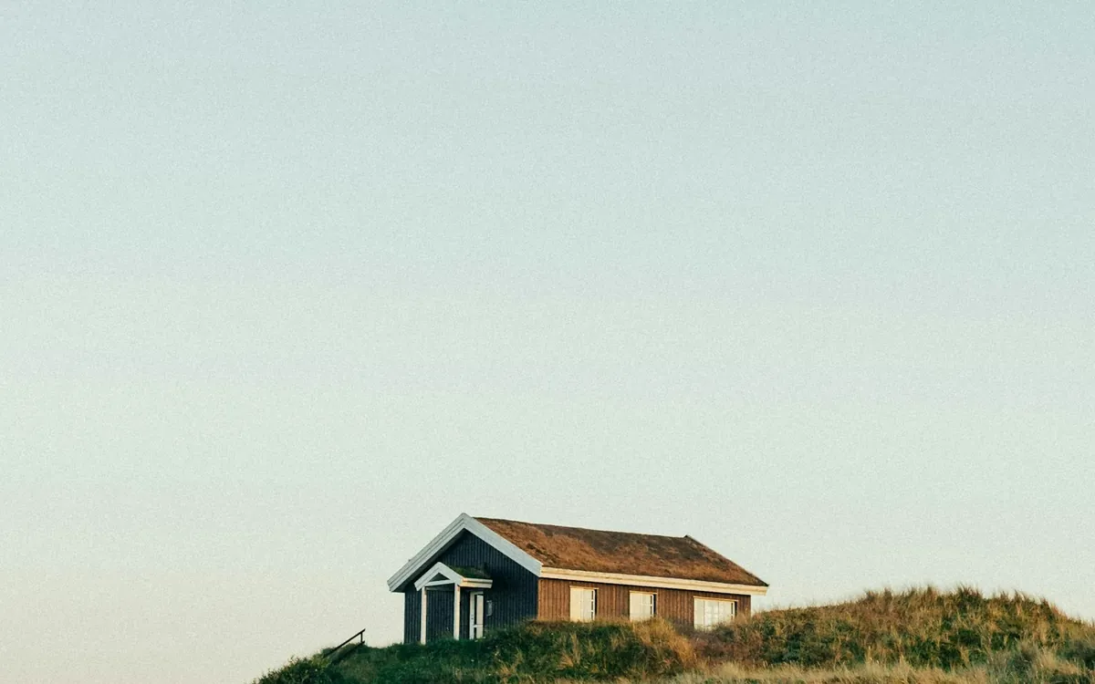 Small house standing on a grassy hill under a pale sky