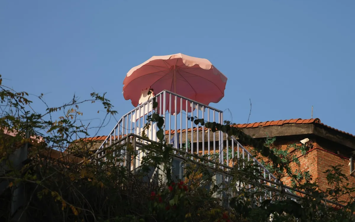 Red umbrella on a rooftop terrace against a deep blue sky