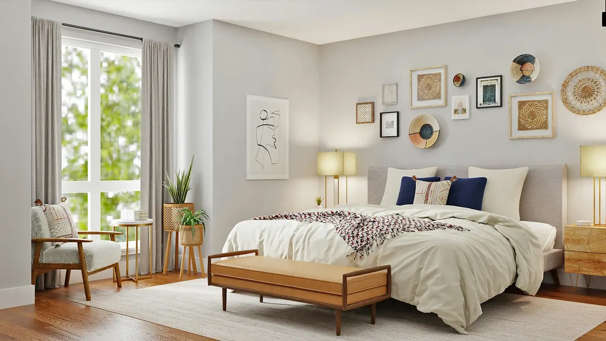 Sunlit bedroom with a white bed, wall frames and a wooden bench