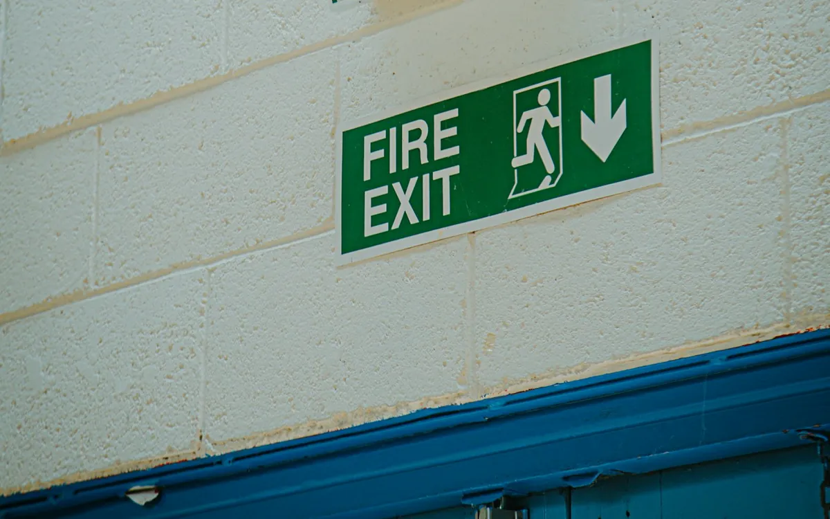 Green emergency exit sign mounted on a building wall