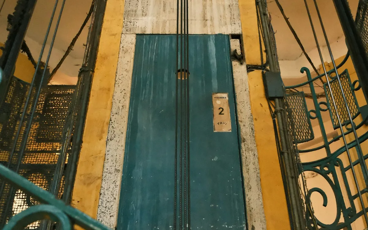 Vintage lift shaft with teal doors and metal railings