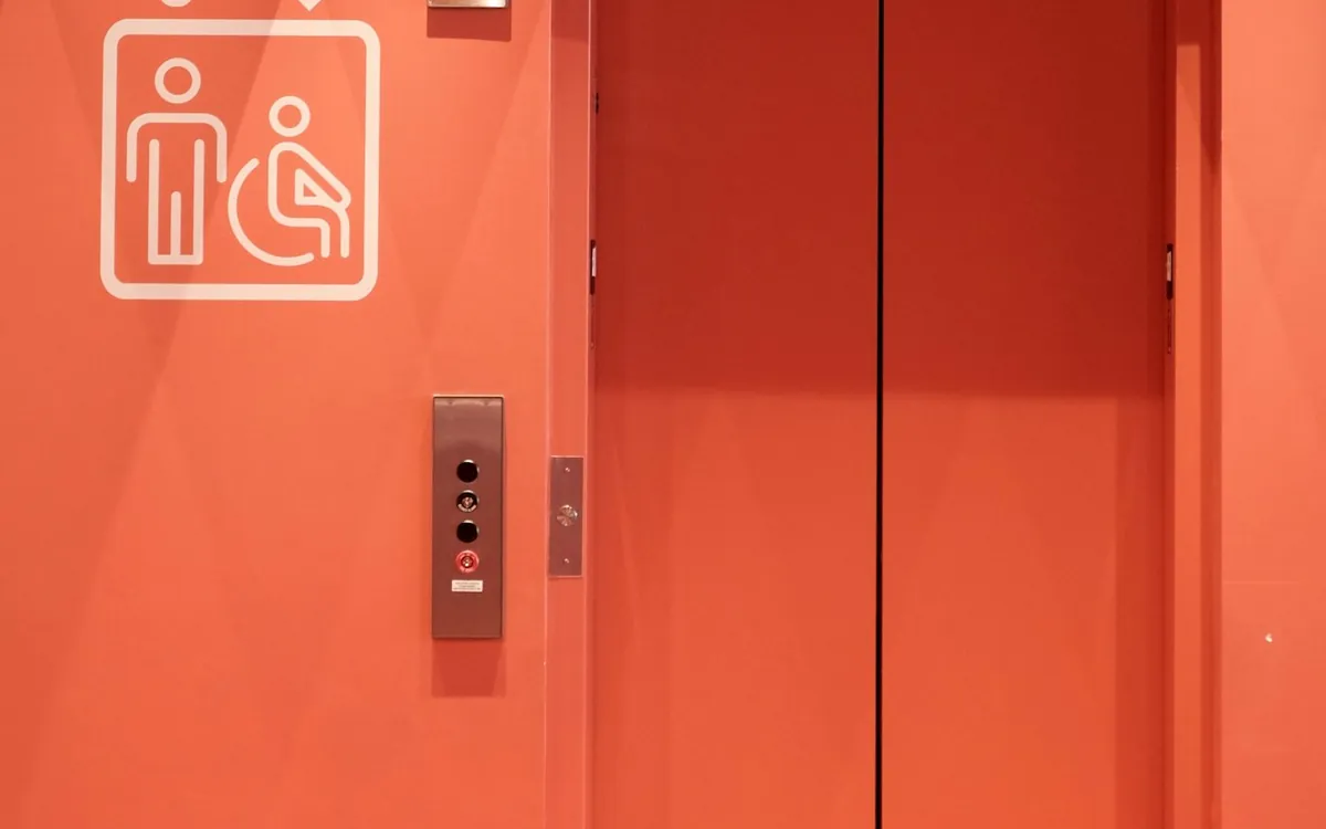 Orange lift doors with an accessibility symbol and call buttons