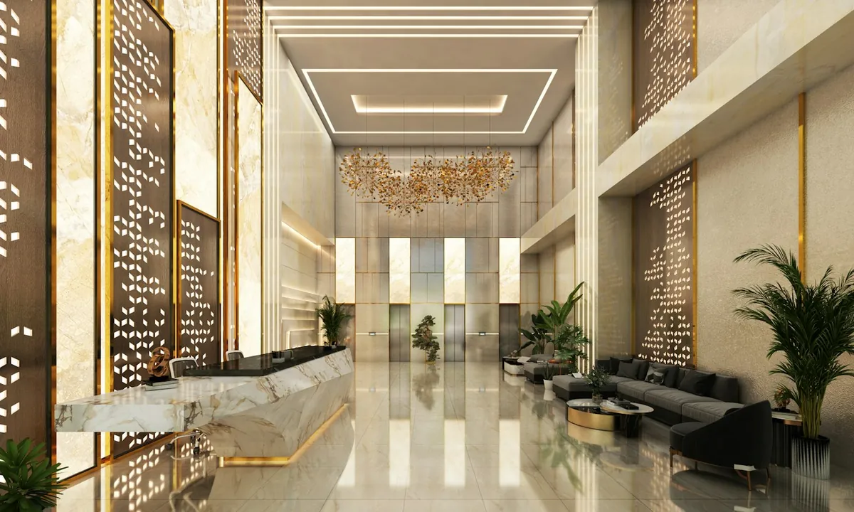 Tall lobby with gold chandelier, marble reception and lifts at the far end
