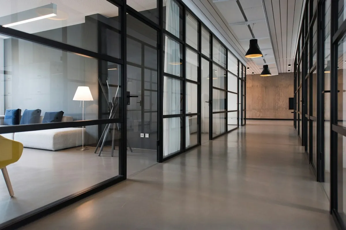 Long glass-walled corridor in a modern building with a lamp and sofa