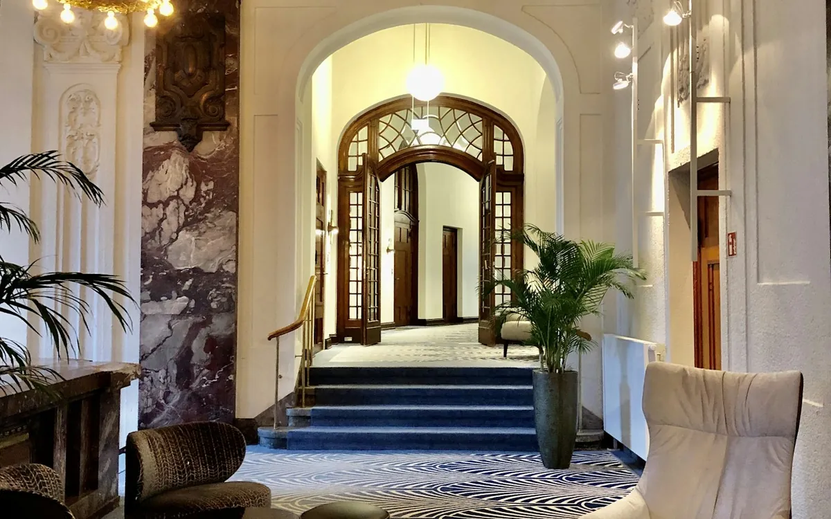 Hotel lobby with patterned carpet, armchairs and an arched doorway
