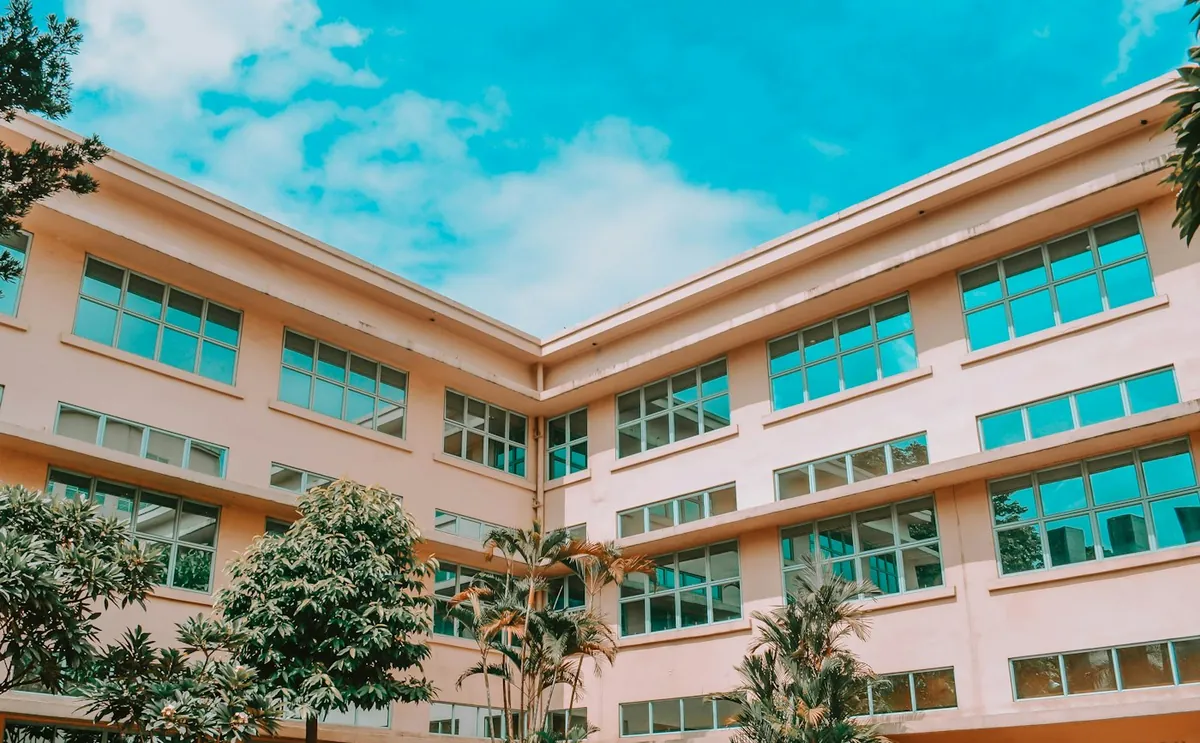 Pink multi-storey school building with rows of blue-framed windows