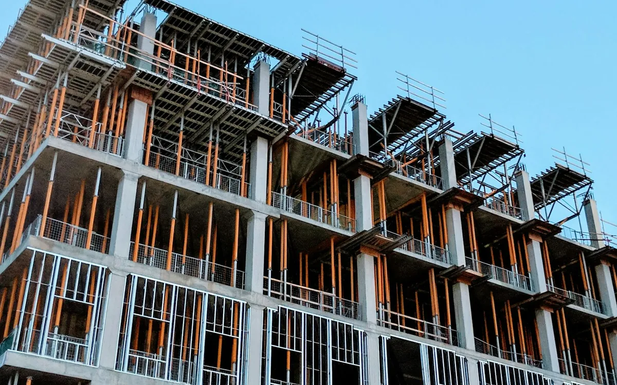 Multi-storey concrete frame building under construction against a blue sky