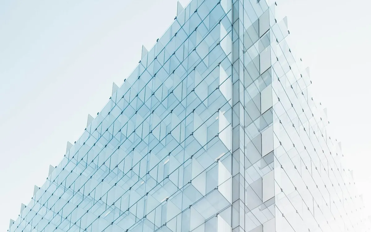 Pale glass-clad building corner rising into a hazy sky