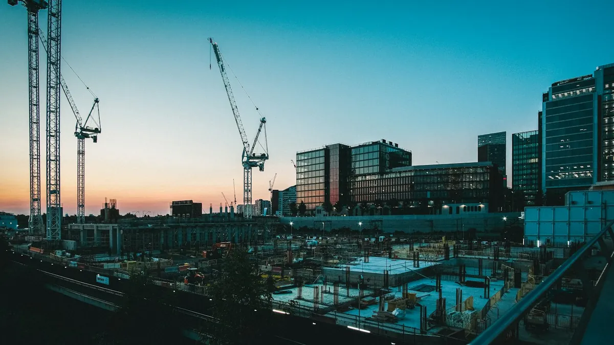 Tower cranes over a city construction site at sunset