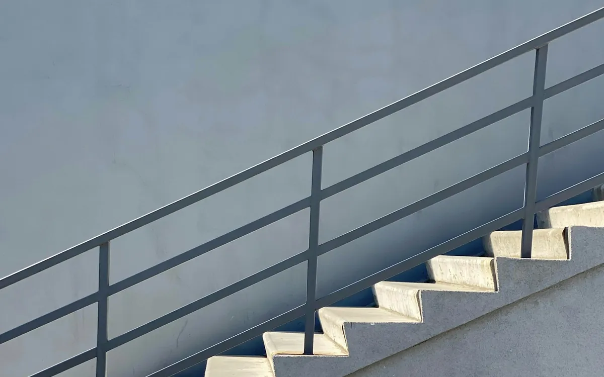 White concrete staircase with a steel railing against a blue-grey wall