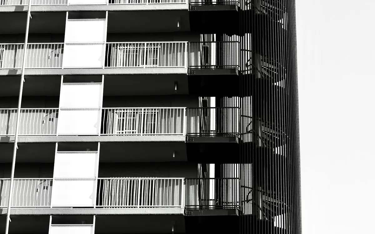 Black and white view of a tall apartment tower with a grid of balconies