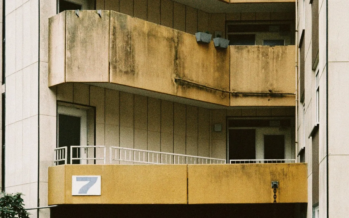 Older apartment building with weathered balconies and a ground-floor entrance