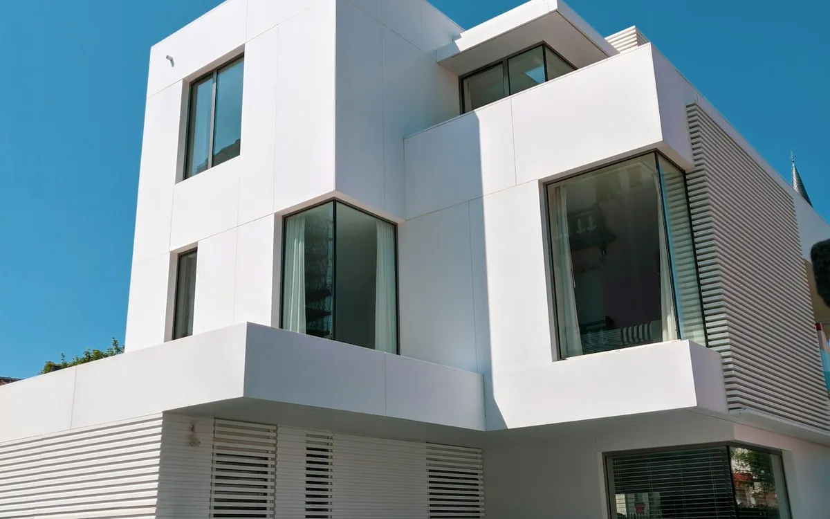 White modern two-storey house with geometric windows against a blue sky