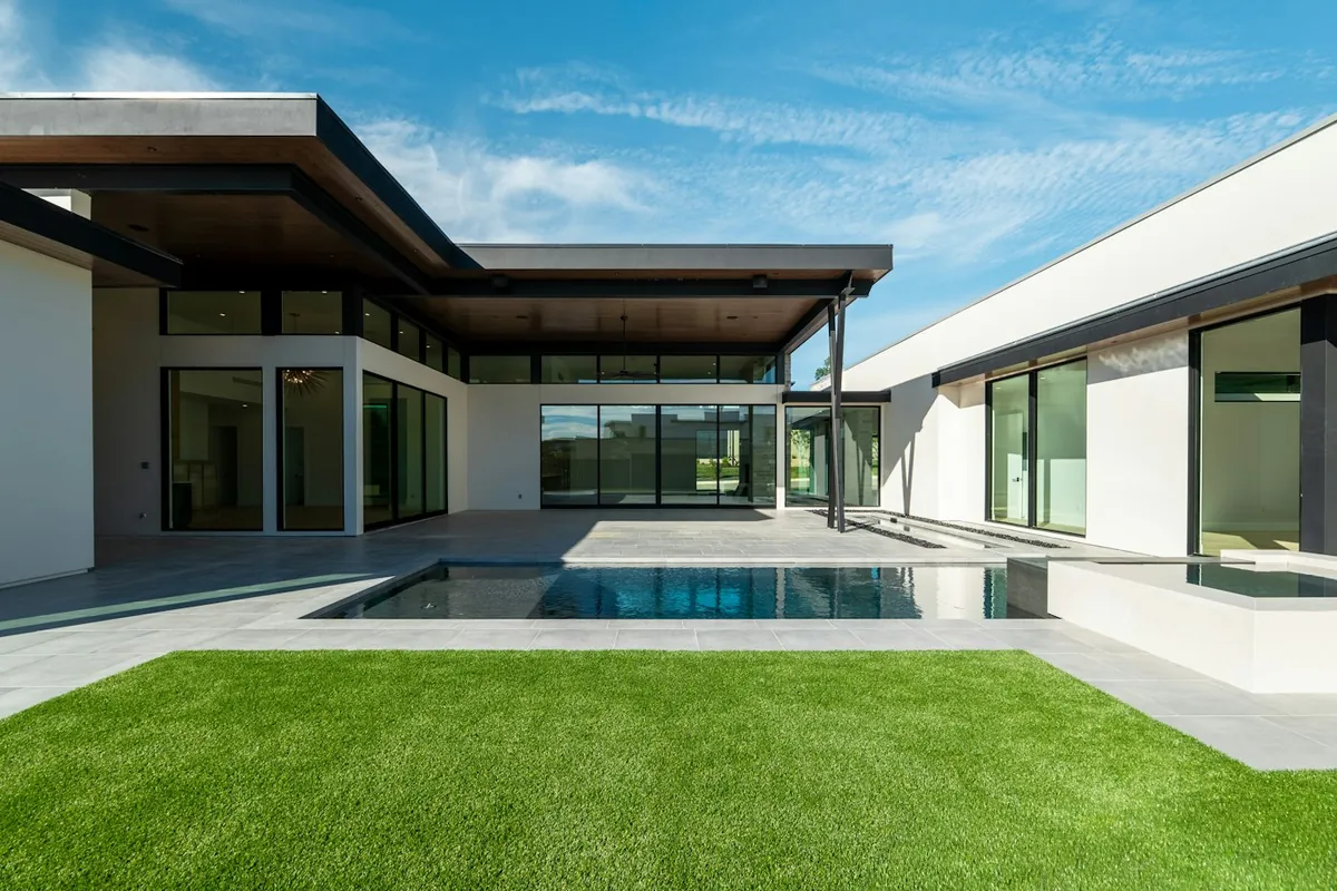 Contemporary house with a pool terrace, glass walls and a grass lawn