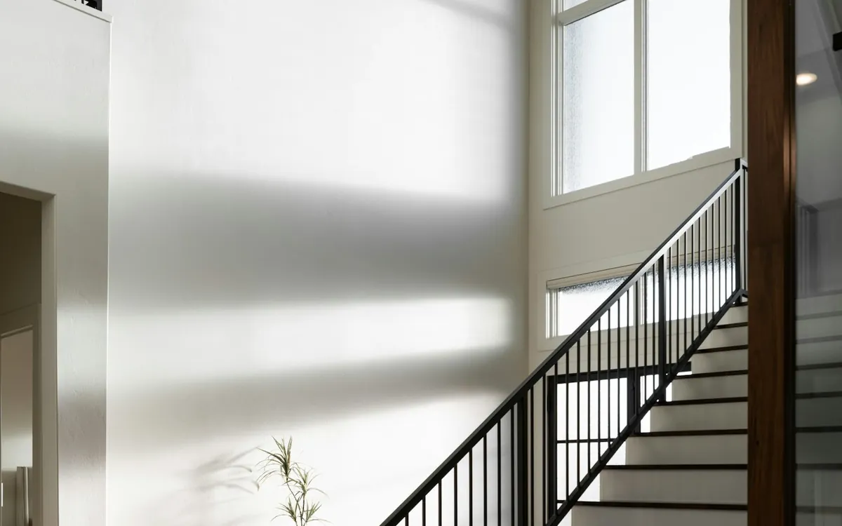 Bright staircase with black railing beneath a high ceiling and a modern chandelier