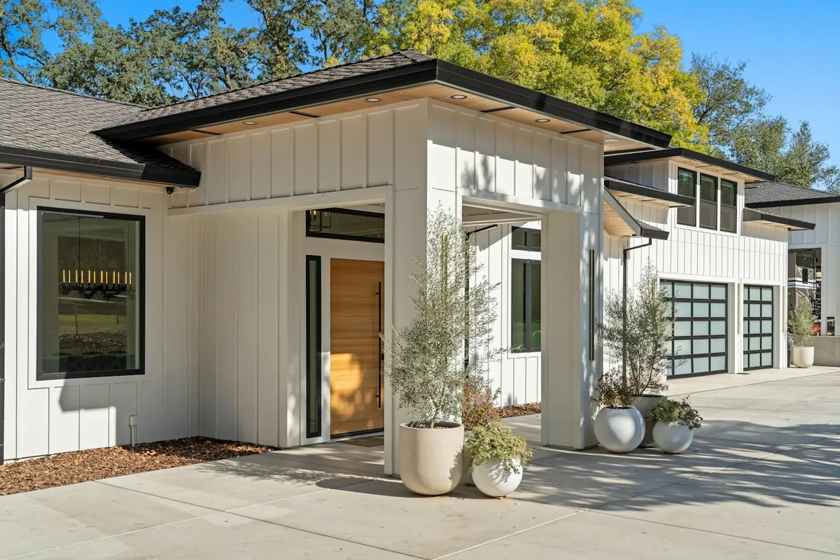 White modern building with timber panelling, glass doors and garden planters