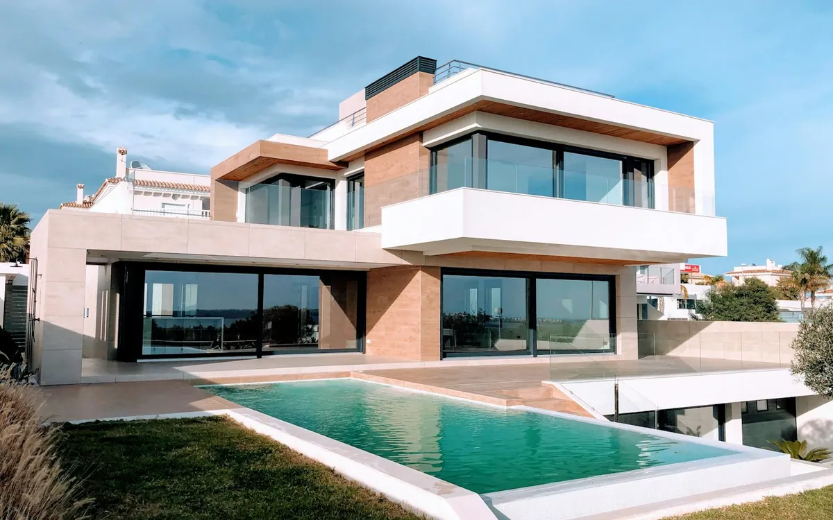 Modern two-storey house with large glass walls, brick details and a swimming pool