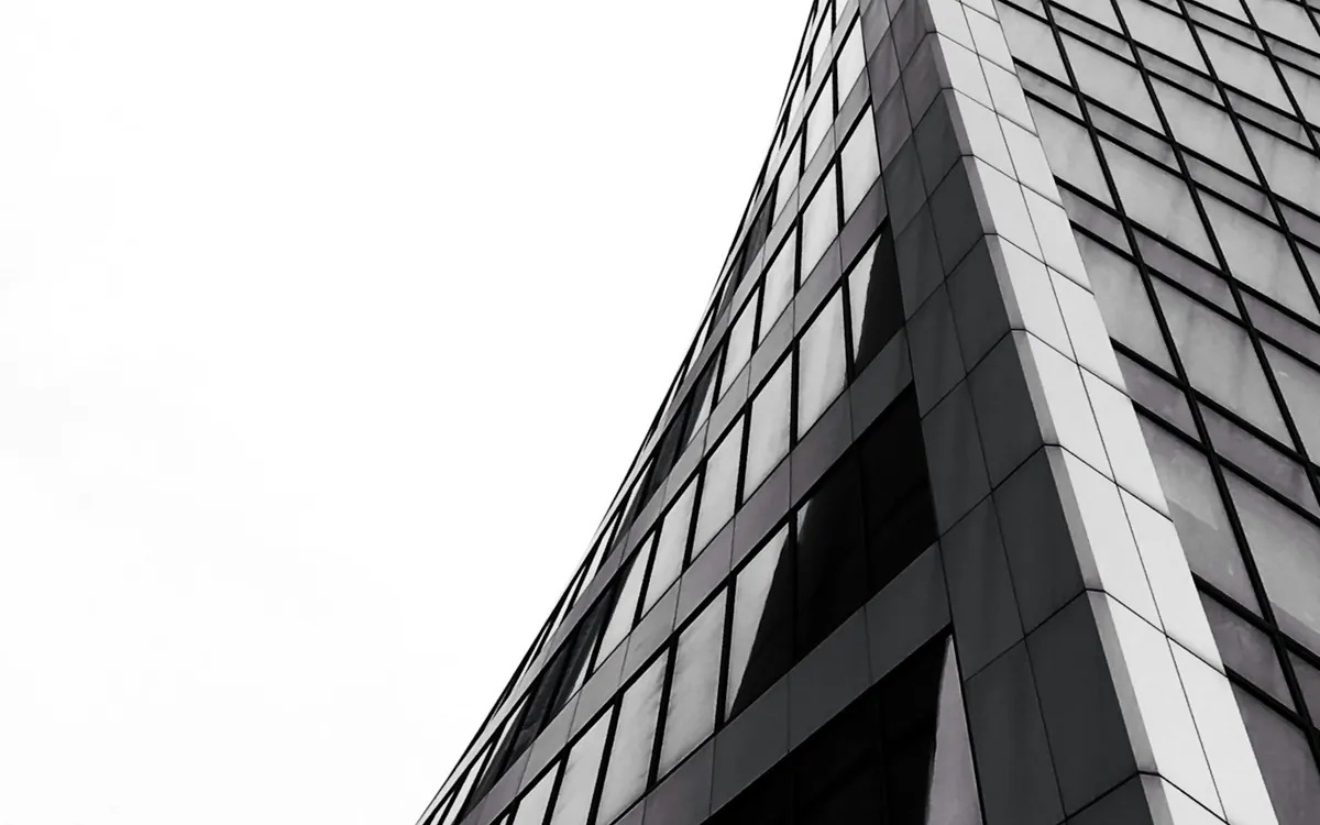 Sharply curved white and glass tower rising against a white sky