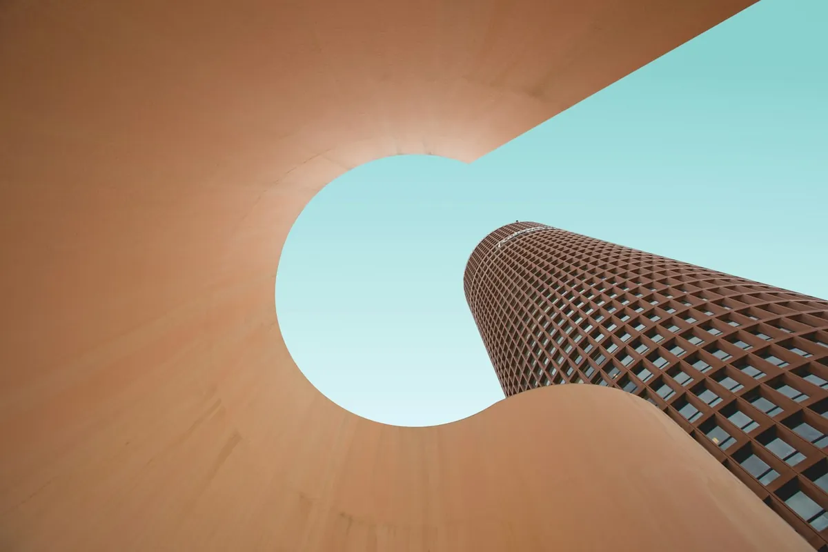 Curved copper-toned walls and a pale blue sky seen through a round opening