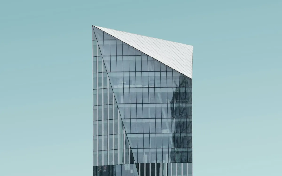 Thin glass tower tip against a pale teal sky