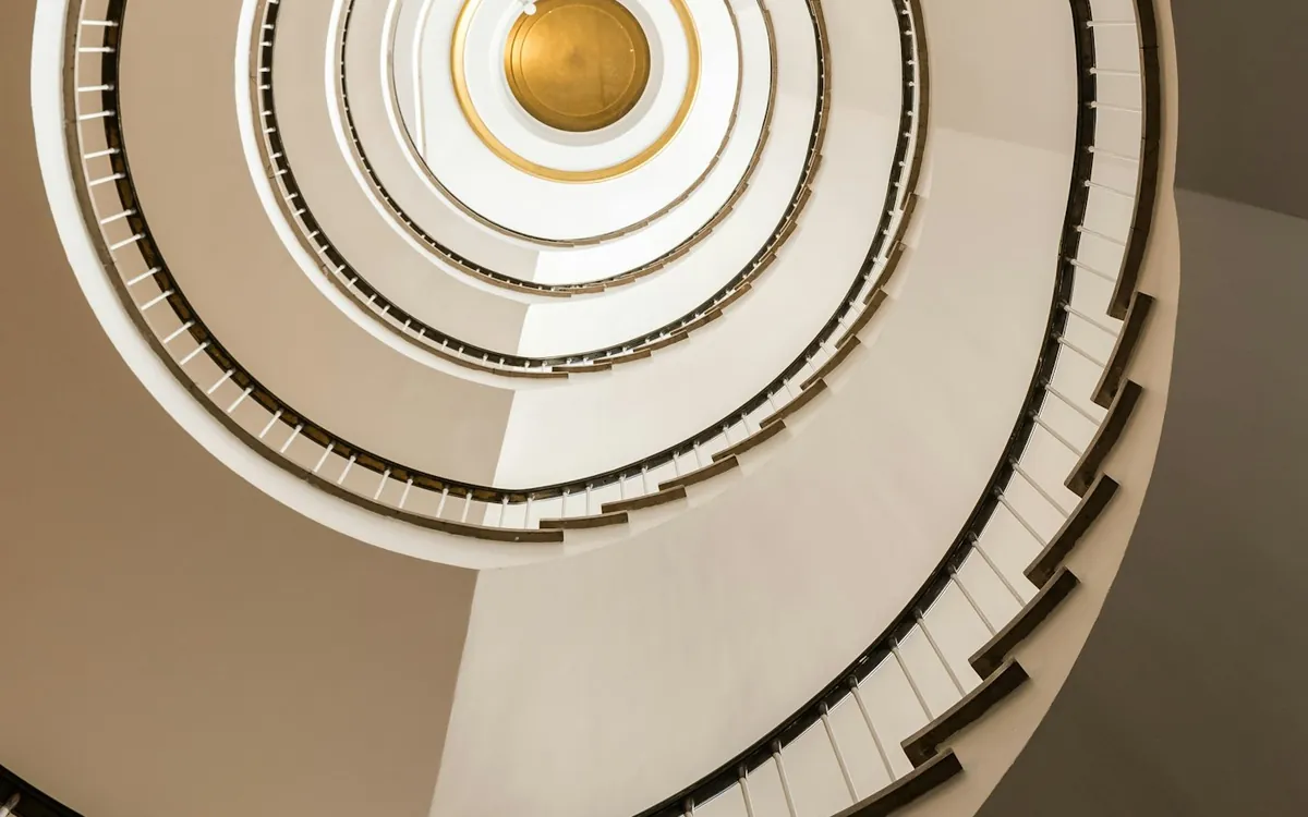 Spiral staircase viewed from above in warm cream tones