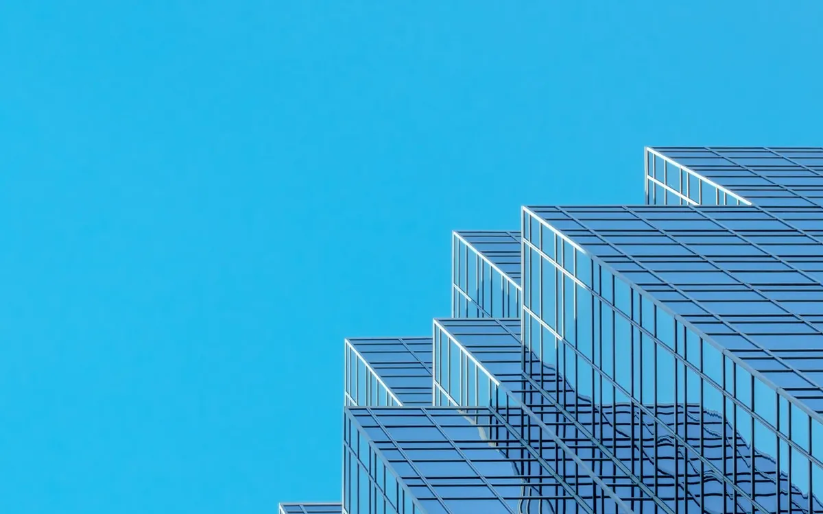 Blue glass high-rise facade with stepped terraces against a bright sky
