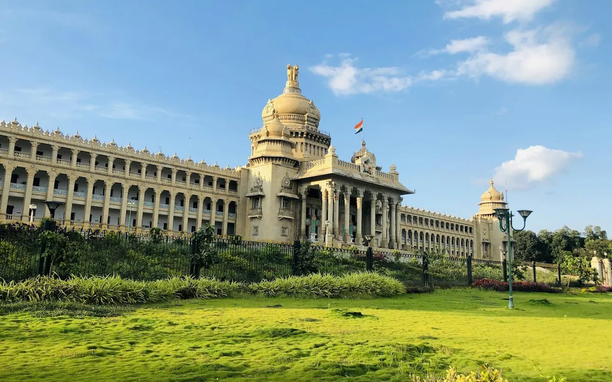 Large golden-domed government building with a green lawn under blue sky in Bengaluru